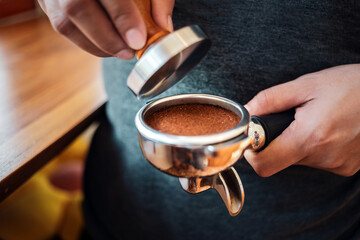 Close-up of hand Barista cafe making coffee with manual presses ground coffee using tamper at the coffee shop