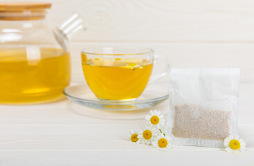 A bag of chamomile tea. Herbal chamomile tea in a bag on a white wooden background. Close-up. Copy...