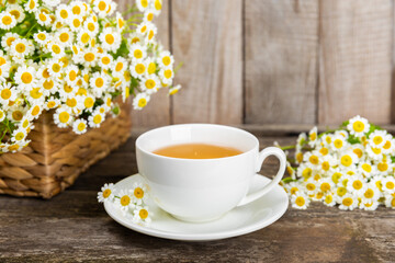 Chamomile herbal tea with flower buds, honey and lemon on a brown wooden table and a bouquet of chamomile. Useful herbal, soothing drinks and natural healer concept. Immunity tea.Close up. Copy space.