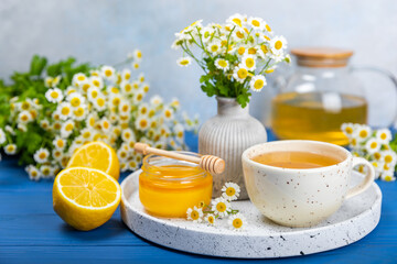 Chamomile herbal tea with flower buds on a blue wooden table and a bouquet of chamomile. Useful herbal, soothing drinks and natural healer concept. Immunity tea.Close up. Copy space.
