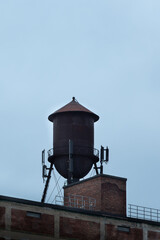 Old water tower on top of brick industrial building against blue sky, Montreal, Quebec, Canada