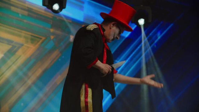 Creepy scary clown mime pretends to cut his hand on stage during TV talent show audition . Broadcast television style TV entertainment program 