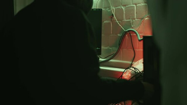 Mysterious cyber security hacker in hoodie in headquarter with computers