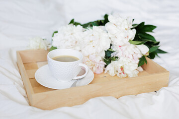 The atmosphere of a romantic morning, coffee in bed with peony flowers