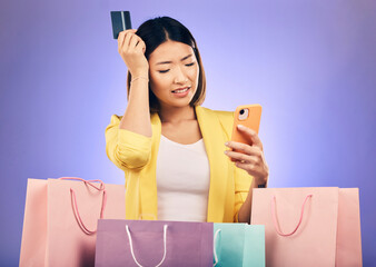 Woman, confused and credit card, phone and online shopping scam, news or fintech payment problem. Stress, retail bag and sad asian person in e commerce mistake on mobile and purple studio background