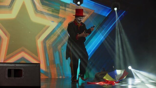 Creepy clown mime showing magic tricks on stage during talent show audition. Broadcast television style TV entertainment program 