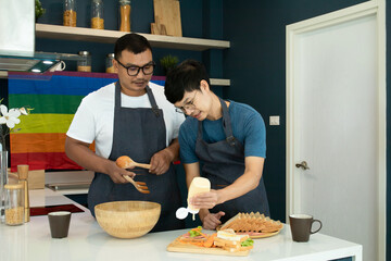 Fototapeta na wymiar Asian LGBTQ+ homosexual man spending time together in kitchen cooking making sandwich, attractive romantic couple having breakfast in morning, cheerful gay lover take care lover enjoy preparing food