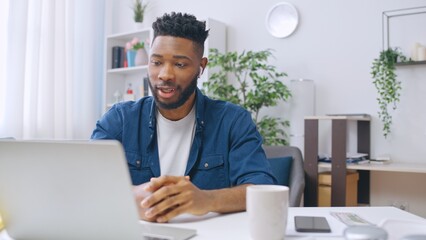 Young African American man in headphones having business call with colleagues, remote work