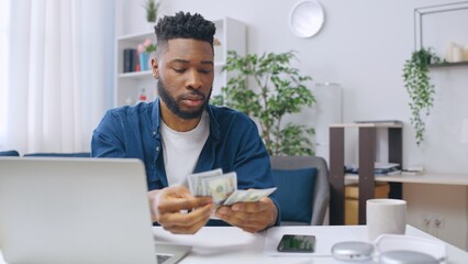 Happy African American man counting money, making savings, planning purchases