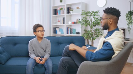 African American psychologist communicating with a teenage boy, child counselling - obrazy, fototapety, plakaty