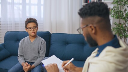 African American male school psychologist talking with a boy, child therapy