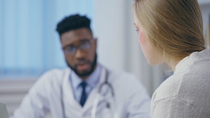 Obraz premium Caring African American doctor consulting injured woman, traumatologist office