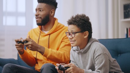 Happy young man playing video games with little brother, family having fun