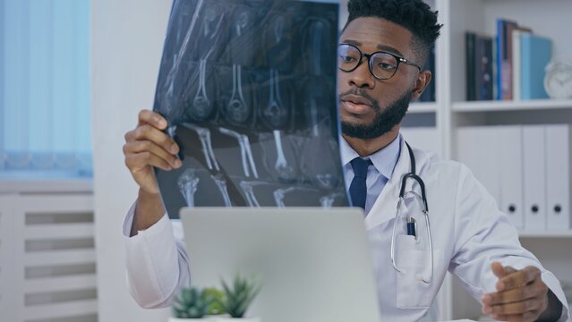 Trauma doctor checking patient's x-ray image, satisfied with treatment
