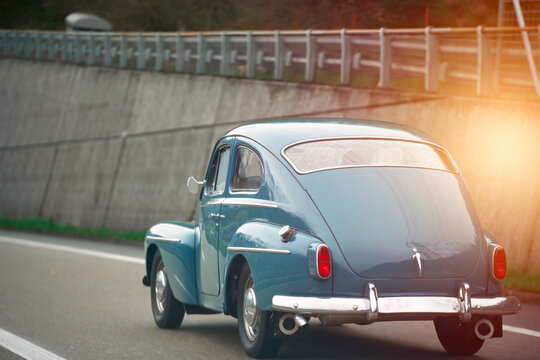 Old vintage European car model on the public highway. Blue oldtimer coupe speeding on the road.