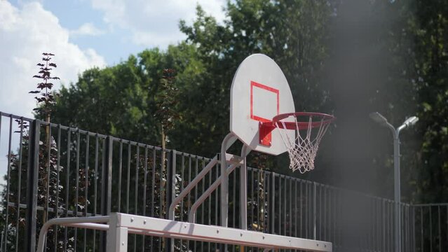 Shield with rim and net on basketball sports ground in urban park. Ball team games score on town street on sunny summer day