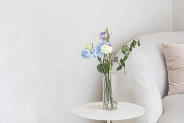 glass vases with flower on ivory table near beige wall.
