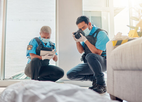 People, police and investigation at the crime scene for murder, victim or case of death at home. CSI man and woman writing notes, pictures or photography for law enforcement or evidence in the house