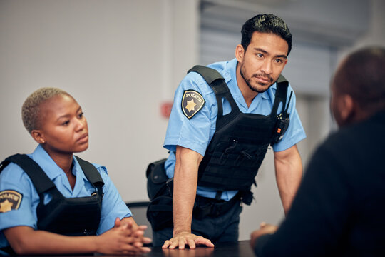 Interrogation, arrest and police team with a suspect for questions as law enforcement officers. Security, crime or investigation with a serious man and woman cop talking to a witness for information
