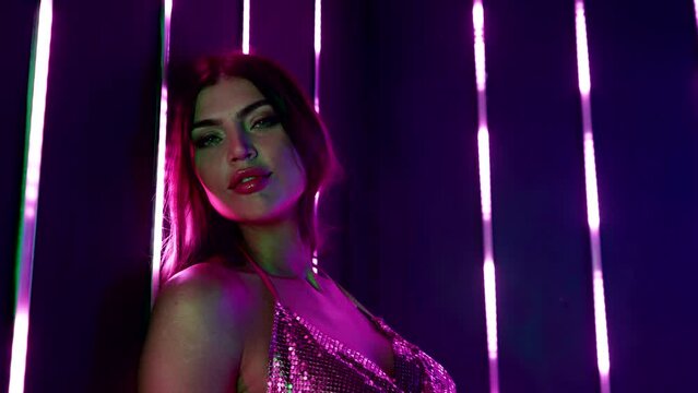 Portrait of a charming young Caucasian woman in neon light. Cute happy model babe. A woman face against the background of LED illumination of neon tubes.