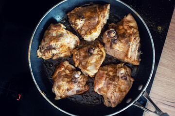 frying pan with chicken pieces on the hob