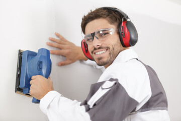 professional construction worker using sander on interior wall