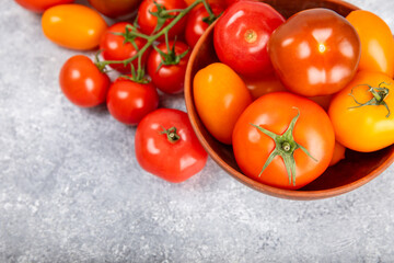 Tomatoes on marble texture background. Cherry tomatoes, yellow, pink, brown and black tomatoes in a bowl. Organic vegetables, harvesting.Vegan. Fresh ripe tomatoes. copy space.