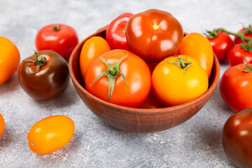 Tomatoes on marble texture background. Cherry tomatoes, yellow, pink, brown and black tomatoes in a bowl. Organic vegetables, harvesting.Vegan. Fresh ripe tomatoes. copy space.