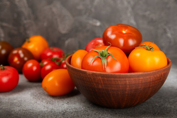 Tomatoes on marble texture background. Cherry tomatoes, yellow, pink, brown and black tomatoes in a bowl. Organic vegetables, harvesting.Vegan. Fresh ripe tomatoes. copy space.