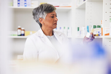 Pharmacist, shelf and a woman reading a medicine box label in a pharmacy for knowledge. Mature female employee in healthcare, pharmaceutical and medical industry to check product information on stock