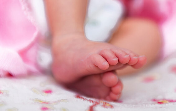 Asian newborn baby feet on white blanket.