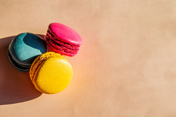Obraz premium Three colorful macaroons isolated on a beige background with copy space 