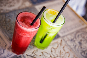 Two colorful cocktails on a table. Red and green smoothie in a bar