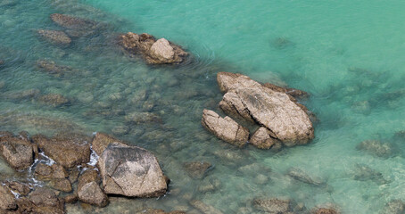 rocks in the shallow, clear waters of Surin beach, Phuket, Thailand