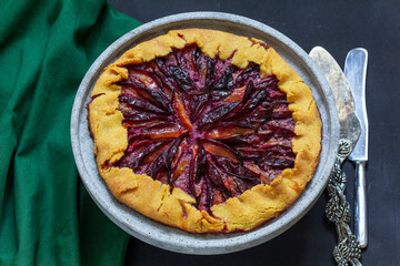 Traditional french pie galette made of corn dough with plum filling on a concrete tray.