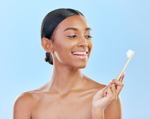 Obraz na płótnie Canvas Face, toothbrush and a woman brushing teeth for dental health on a blue background for wellness. Happy indian female model with toothpaste and brush for a clean, fresh and healthy mouth in studio