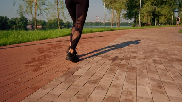 close up female legs woman jogging along the river in summer park aerobic exercise in the morning slow motion
