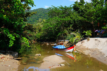 Small fishing boat on a creek coming out of the jungle on Khlong Chak Beach, Koh Lanta Yai island, Krabi province, Thailand