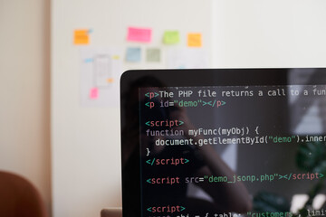 Still life of PC screen with javascript coding demo, on desk in office