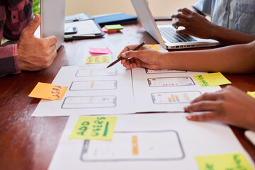 Close up of hands writing notes on mobile app layout design, coding tech