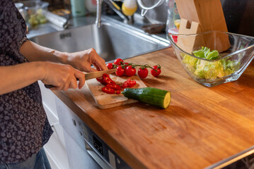 person preparing food in kitchen, person cutting vegetables in kitchen
