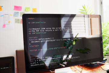 Still life of PC screen with javascript coding demo, on desk in office