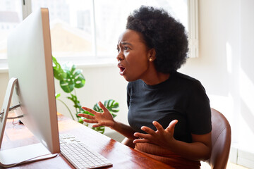 Frustrated and upset young developer shouts at screen, Black woman in tech