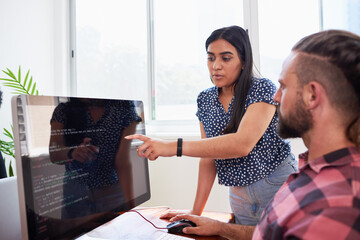 Two developers peer programming together in office, assisting peer review