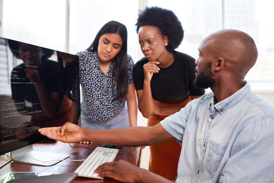 Three developers peer programming together in office, assisting peer review
