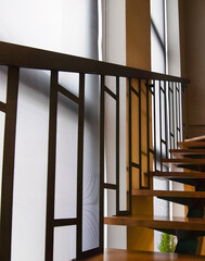 Roller blinds on floor-to-ceiling windows near the stairs to the second floor. Wooden staircase with illuminated steps and metal railings. Sunscreen shades from prying eyes on the stairwell.