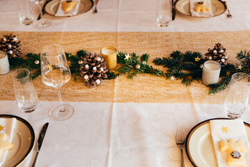 Dinner table festively decorated with candles and pine cones to celebrate Christmas Eve.