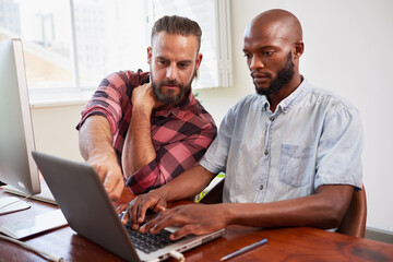 Two developers peer programming together in office, coding side by side