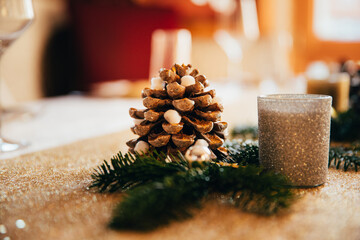 Dinner table festively decorated with candles and pine cones to celebrate Christmas Eve.