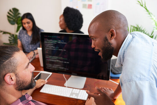 Two developers peer programming together in office, assisting peer review